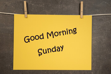 Napis good morning Sunday na wiszącej żółtej kartce na ciemnym tle