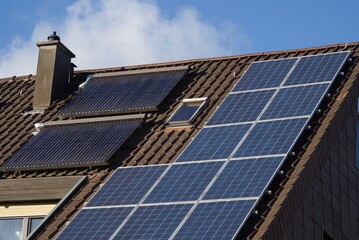 Obraz premium Solarthermie und Solarmodule auf einem Dach in der Frühlingssonne