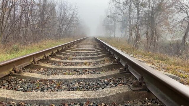 Empty railway track in gloomy weather, light fog in autumn. No train. Mystique on the railway. Panorama of the tracks, a view of the sleepers, the railway track. No people. High quality 4k footage