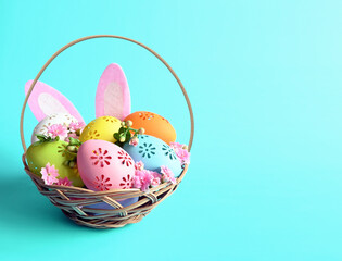 Multi colors Easter eggs in the basket with bunny ears and flowers on blue background. Pastel color Easter eggs.