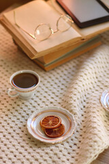 Plate of cookies, cup of tea, fresh blueberries, dry oranges, stack of books, reading glasses and tablet on the table. Hygge at home. Selective focus.