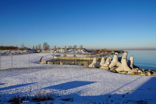 View to the Baltic sea coast with wave brakers during winter time with ground covered with white snow. Tallinn, Estonia. January 2023