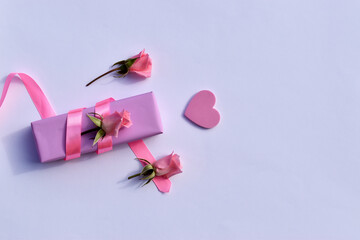 Love concept. A composition made of a gift box, pink roses and a heart on a white background. Valentine's Day. Copy space.