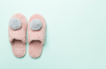 Soft pink slippers on color background, top view
