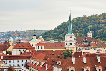 Fototapeta premium Orange tile roofs and church view, and historical buildings in Prague.
