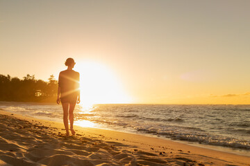 Woman walking on a beautiful Hawaii beach at sunset 