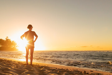 It's a beautiful life! Young woman looking out to the ocean sunrise finding peace happiness in...