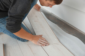 Worker installing new laminate flooring in room, closeup