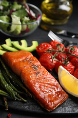 Tasty cooked salmon and vegetables served on black table, closeup. Healthy meals from air fryer
