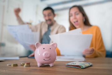 Amazed young couple celebrate good financial news, paper documents account balance mortgage approval