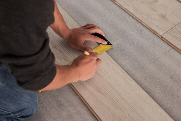 Professional worker using ruler during installation of laminate flooring, closeup. Space for text