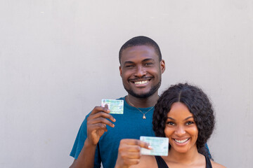 Two Nigerian citizens, male and female holding their voters card, PVC, smiling and happy
