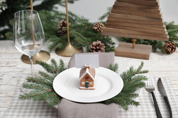 Festive place setting with beautiful dishware, cutlery and gingerbread house card holder for...
