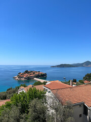 Fototapeta na wymiar View of the island of Sveti Stefan in the Bay of Kotor over the roofs of old coastal houses. Montenegro