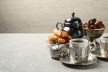 Tea, baklava dessert and date fruits served in vintage tea set on grey table, space for text