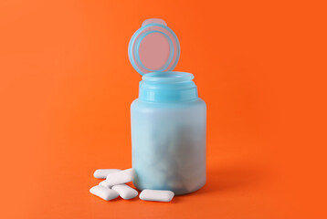Jar with chewing gums on orange background