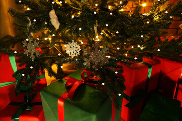 Beautifully wrapped gift boxes under Christmas tree indoors, closeup
