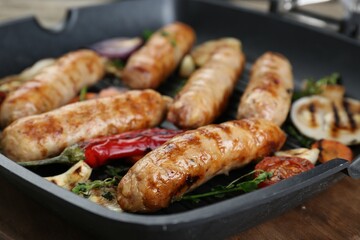 Tasty fresh grilled sausages with vegetables on wooden table, closeup