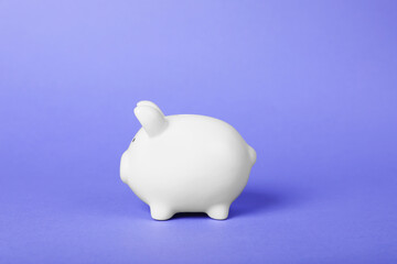 Ceramic piggy bank on purple background. Financial savings