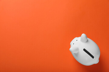Ceramic piggy bank on orange background, top view with space for text. Financial savings