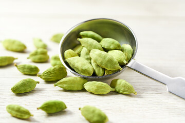 Green cardamom pods on a white wooden table, selective focus.