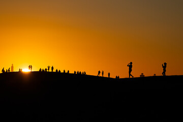 Fototapeta na wymiar Sunset at Maspalomas Dunes - people shadows at clear sky at sunset