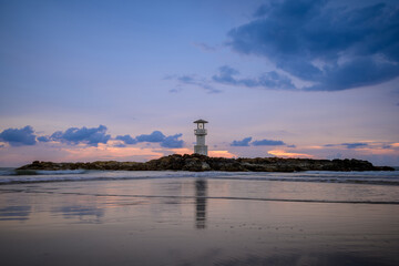 The lonely lighthouse on the rock with evening sun.