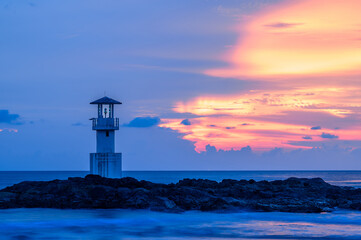 The lonely lighthouse on the rock with evening sun.