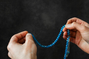 Muslim man praying blue rosary between his hands, worshiping in the month of Ramadan
