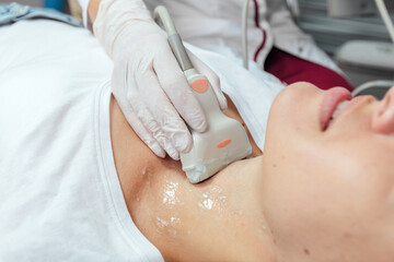 Young woman patient during the ultrasound examination of a thyroid lying on the couch