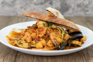 Tempting meal of cioppino with generous amounts of shrimp, mussels, scallops, and clams served on a wide plate