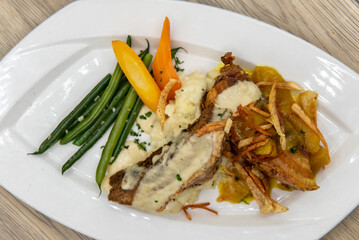 Overhead view of tempting meal of slow roasted pork belly served with creamy polenta on a generous sized plate