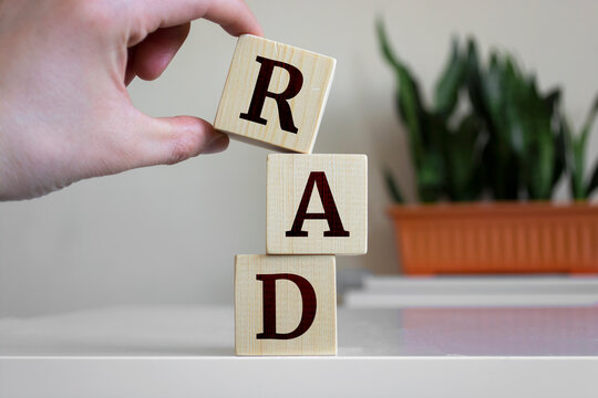 Hand holding wood cube block with 'RAD' text. RAD - short for Rapid Application Development