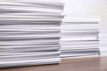 Stacks of white paper sheets on wooden table, space for text