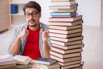 Young male student and too many books in the classroom