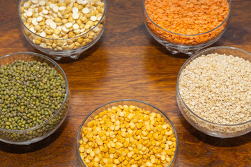 Bowls full of varieties of pulses spread over a wooden table with copy space