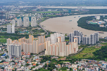 Fototapeta na wymiar Aerial view of a high rise city apartment complex alongside a wide river winding through Ho Chi Mihn City in Vietnam