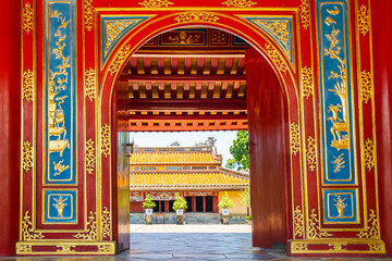 Looking through a golden arched entrance to an ancient temple at Hue in Vietnam