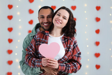 Lovely couple with pink paper heart indoors. Valentine's day celebration