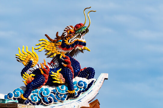 Golden gragon statue on red pillar in the shrine with blue sky.