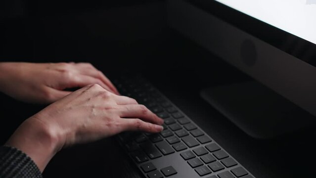 暗い部屋でタイピングする女性