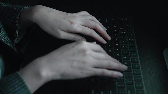 暗い部屋でタイピングする女性