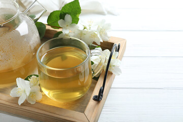 Cup of tea and fresh jasmine flowers on white wooden table