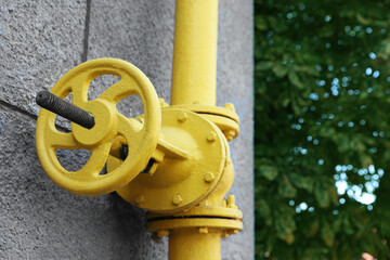 Yellow gas pipe on grey wall outdoors, closeup. Space for text