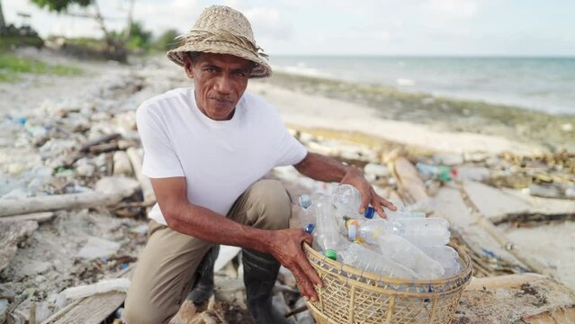 Senior asian man happy to clean beach from plastic bottles and ocean trash