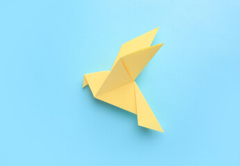 Origami art. Beautiful handmade paper bird on light blue background, top view