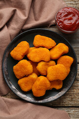 Tasty chicken nuggets with ketchup on wooden table, top view