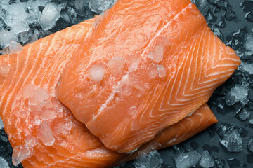 Fresh raw salmon with ice on black table, flat lay