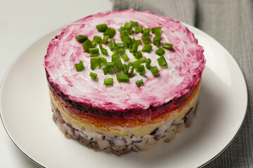 Herring under fur coat salad on white table, closeup. Traditional Russian dish
