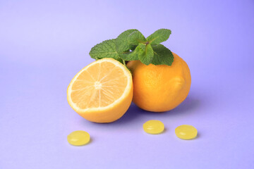 Fresh lemons, mint leaves and cough drops on lilac background